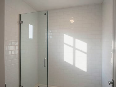 Wide shot of a completed bathroom renovation — clean white subway tile, frameless glass shower panel, natural window light casting soft shadows, no people or styling props