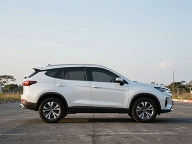 Exterior side profile of a clean SUV on an empty paved lot in daylight, Chiriquí setting, wide framing with open sky above