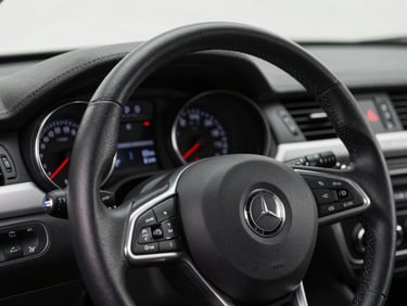 Close-up of a car dashboard and steering wheel under clean studio lighting, sharp focus on instrument cluster, interior detail shot