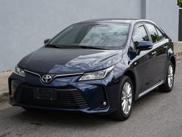Front three-quarter shot of a dark blue Toyota Corolla parked on clean asphalt in daylight, Chiriquí, sharp detail on front grille and headlights