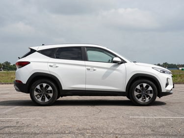Side profile of a white Hyundai Tucson SUV parked in an open lot under bright overcast Panamanian daylight, clean background, full vehicle visible