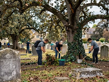 A wide shot of volunteers in outdoor gear working together to clear ivy from a sun-dappled historic cemetery under mature oak trees.
