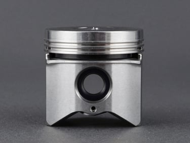 Crisp studio shot of a high-performance car piston on a dark gray background, technical lighting