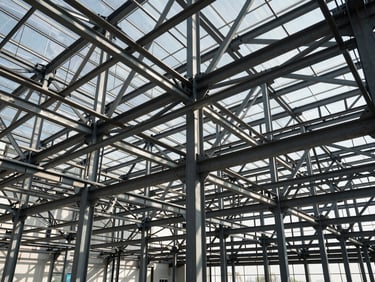 Wide-angle architectural view of a commercial steel framework under high-contrast daylight, showing geometric structural patterns