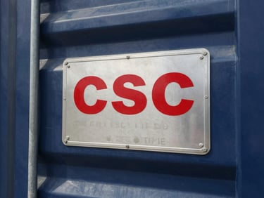 Close-up of a metallic CSC safety approval plate on a corrugated steel container door, showing structural details and certification stamps, sharp focus