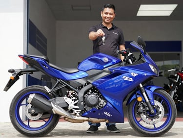 A happy customer receiving the keys to a brand new blue Yamaha motorcycle inside the clean showroom on Cra 20, bright natural daylight.