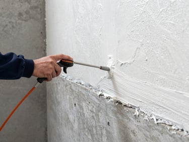 Detail shot of a technician spraying high-performance polyurethane insulation onto a concrete basement foundation wall, clean work environment, high-visibility lighting