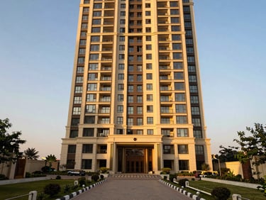 Exterior of a premium apartment tower in Emaar sector Mohali, shot at golden hour from pavement level, warm facade, landscaped entry drive in foreground