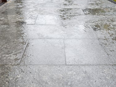 Close-up of a clean, freshly pressure-washed stone driveway, bright overcast daylight, water droplets on the surface, crisp architectural photography, sharp details