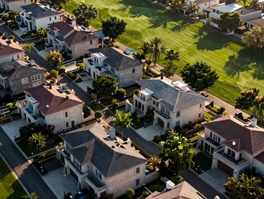 Aerial view of a high-end gated community with luxury homes, green landscaping, and shared amenities like a golf course, crisp natural daylight, high contrast.