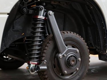 Technical close-up of a heavy vehicle chassis and suspension linkage, showing the steel grain and robust construction under high-contrast industrial lighting.