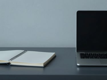 Minimalist interior shot of an organized desk with a laptop and clean notebook in cool overcast daylight.