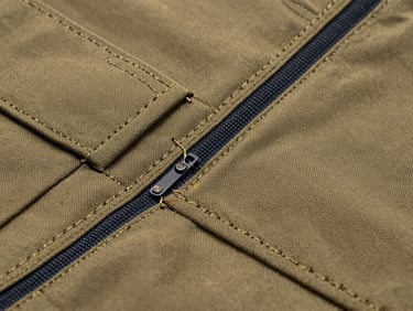 Crisp studio photography macro detail of triple-stitched seams on a heavy-duty khaki industrial canvas work jacket, sharp high-contrast light, 85mm