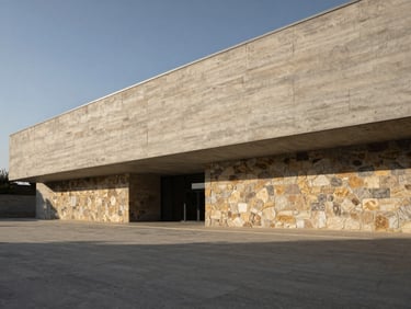 Wide panoramic architectural shot of a minimalist concrete and stone building exterior under dramatic low-angle daylight