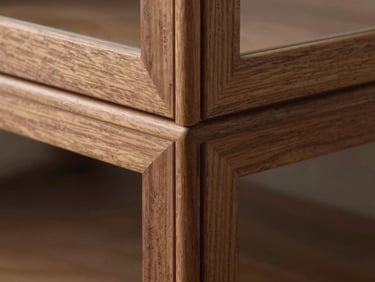 Detail shot of a commercial display cabinet corner joint in walnut, showing finger-joinery precision and flush hardware, close macro framing with soft natural sidelight revealing wood grain, no people
