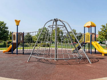 Environmental shot of a public park playground in Germany featuring heavy-duty climbing nets and galvanized steel frames, bright natural daylight