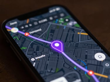 Close-up of a smartphone screen showing a live GPS map with a glowing neon purple vehicle position marker and animated route path over a dark map layer, coordinate data visible, no text labels, cinematic lighting, deep focus