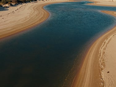 Cinematic wide drone shot of the calm saltwater lagoon, deep blue water contrasting with golden sand banks, midday light.