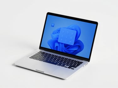 Overhead flatlay of a clean digital workspace, laptop screen displaying vector design shapes, electric blue tones, soft shadows