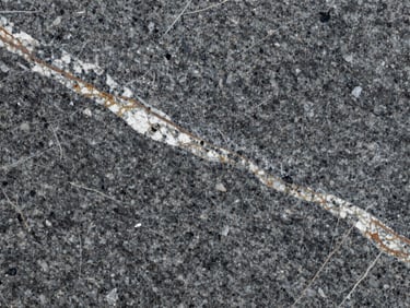 Macro texture of polished deep grey granite slab with rich white and terracotta veining, high contrast, structural detail.