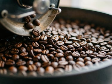 Close-up of coffee beans tumbling from a warm roaster, rich espresso brown tones, tactile texture