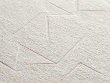 Abstract macro photograph of heavy, textured cotton paper with a clean geometric blind debossing, professional and understatedly luxurious.