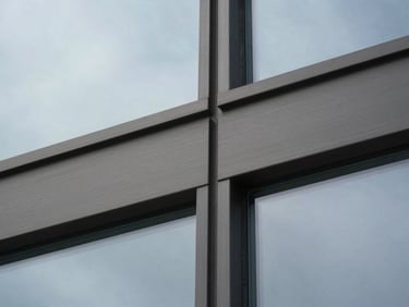A close-up macro shot of brushed dark steel and structural glass panels, clean architectural grid, cold overcast daylight