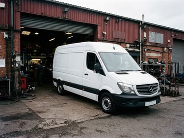 A clean white commercial van parked outside a high-contrast industrial workshop bay, overcast daylight, sharp details, 35mm