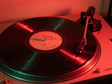 Close-up of a vinyl record spinning on a turntable under harsh red neon light