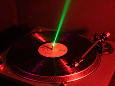 Vinyl record spinning on a turntable in a dark studio, illuminated by a single sharp green laser beam, dust particles visible, high contrast