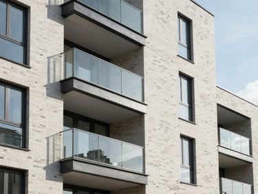 Architectural detail of a modern, clean UK residential development facade, highlighting clean brickwork, glass balconies, and soft natural daylight.