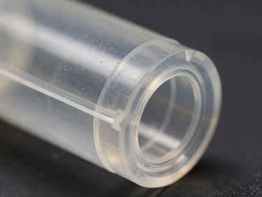 Close-up of a translucent engineering polymer component, showing intricate internal features, against a dark industrial background.