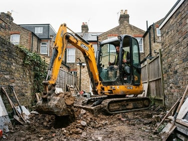 Low-angle heroic shot of a yellow mini excavator operating in a tight London residential backyard, bright overcast daylight, high contrast yellow and charcoal tones, sharp focus, 35mm