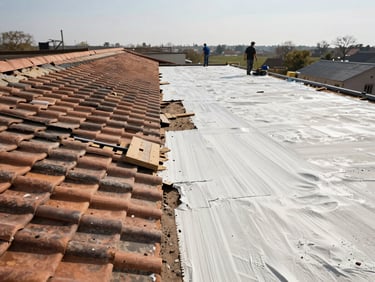 Wide shot of a roof mid-renovation, old tiles removed on one half and fresh underlayment being laid on the other half, workers in the background in daylight
