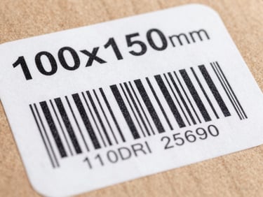 High-contrast shot of a 100x150mm shipping label on a cardboard box, showing clear printed text and barcode