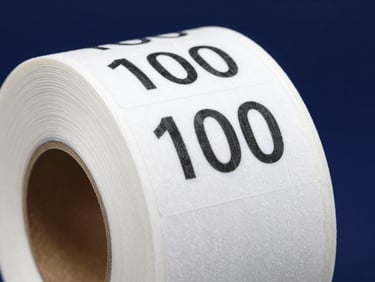 Close-up shot of a pristine 100x50mm direct thermal label roll, sharp clean edges, white paper contrasting sharply with deep navy background, cool industrial lighting