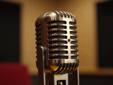 Extreme close-up of a high-end vintage tube microphone in a dark, moody recording booth, soft golden background glow, anamorphic lens