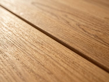 Extreme close-up of a hardwood floor seam, two planks meeting at a precise joint, grain directions subtly diverging, warm golden-hour sidelight making the wood texture three-dimensional, no context objects