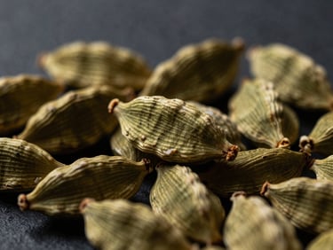 Macro close-up of green cardamom pods in a heap, dramatic side lighting, rich textures, deep slate background, 35mm