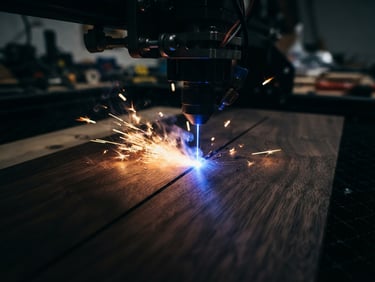 Extreme close-up of a laser engraving head emitting a sharp blue light onto a dark walnut plank, glowing copper sparks, moody workshop setting, macro depth of field.