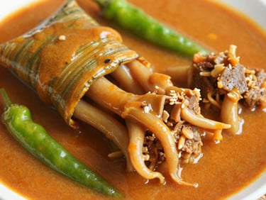 Close-up of Nasi Bungkus Gulai Tunjang package, rich orange gravy pooling around tender tendon, green chilies.