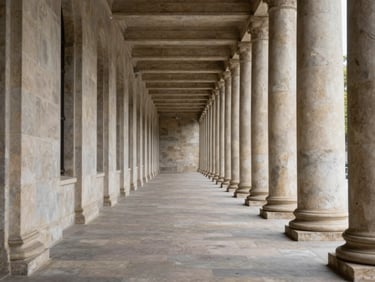 Wide architectural view of a symmetrical stone corridor, receding columns, north-facing daylight, no people, formal and unhurried