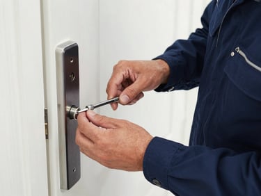 Close-up of a professional locksmith in a clean navy uniform carefully inserting a precision tool into a modern door lock, daytime lighting