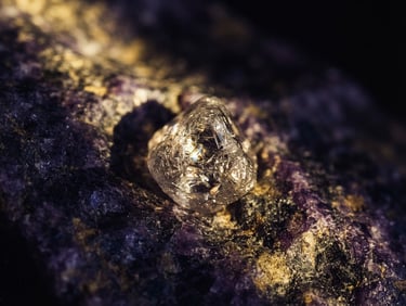 Macro photograph of a raw diamond crystal embedded in deep violet stone, sharp shafts of golden light cutting through shadows, fine art editorial style, 35mm.