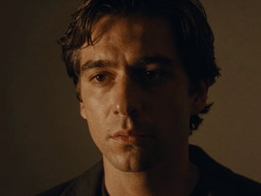 Cinematic close-up of a character actor in low-key lighting, warm amber spotlight highlights, 35mm film photography, shallow depth of field