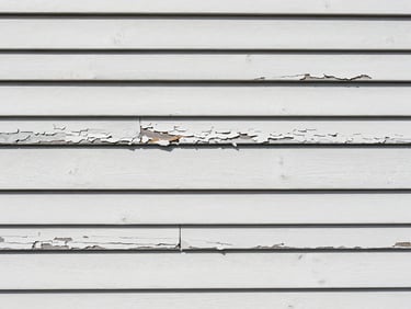Close-up of weathered, peeling exterior wood siding on a Mobile home before preparation, harsh daylight, showing cracks and decay