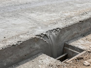 Close-up of poured concrete road surface and drainage channel under construction in Accra, daylight, engineering detail visible, no people
