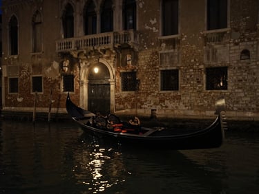 A dark Venetian canal at night, a single black gondola floating near a decaying gothic palace entrance, low-key candlelight reflecting on water