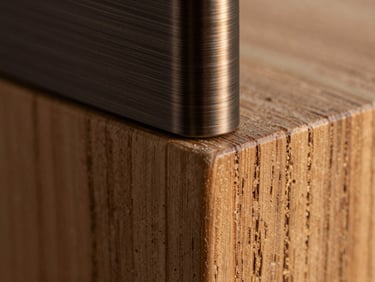 Extreme macro detail shot of dark brushed bronze joining textured raw oak wood, warm soft twilight lighting, highlighting material craft and physical precision.