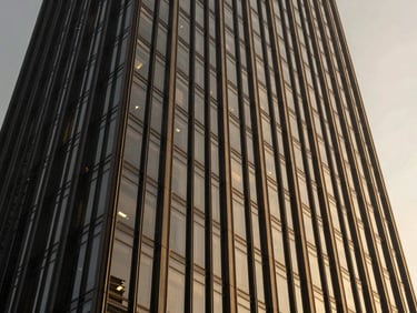 Dramatic architectural rendering of a renovated skyscraper facade, showing new glass and steel elements, high-contrast lighting, deep charcoal and desaturated gold tones, sharp focus